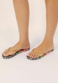 Gouden flip-flops met textuurstraps, voorzien van een bloeien en luipaardprint zool. De voetbed heeft een gladde afwerking die de levendige kleuren accentueert.
