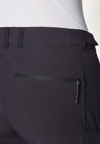 Black athletic pants featuring a zippered pocket, smooth texture, and flat waistband design. Includes belt loops and sleek stitching details.
