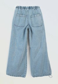 Jasnoniebieskie dżinsowe spodnie o szerokich nogawkach z elastycznym paskiem w talii, dwoma tylnymi kieszeniami oraz regulowanym ściągaczem u dołu nogawek. Miękka faktura, casualowy design.