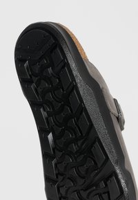 Σόλα γκρι παπουτσιού τύπου slip-on με ανθεκτικό μαύρο μοτίβο πέλματος και ορατό χείλος φελλού στην ανοιχτό γκρι επιφάνεια.