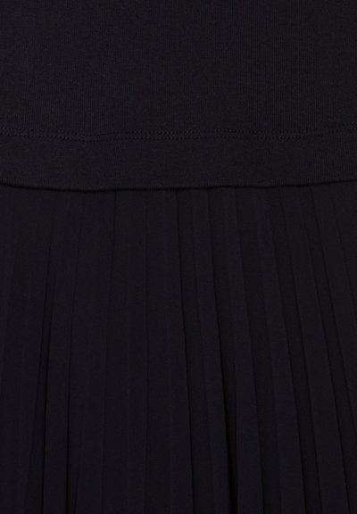 Falda negra con pliegues y una cinturilla ajustada y suave en la parte superior. La tela parece suave y fluida, con finos pliegues verticales a lo largo de toda la falda.