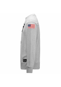 Felpa grigia con maniche lunghe, polsini a coste e un'etichetta con la bandiera americana ricamata sulla spalla sinistra. Presenta un logo sulla parte anteriore.