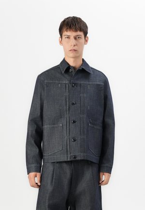 Donkerblauwe denimjas met knopen, twee voorzakken en contrasterende stiksels. Heeft een puntige kraag en een rechte snit.