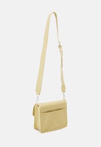 Borsa a tracolla gialla intrecciata con una finitura texturizzata, chiusura a patta magnetica, tasca frontale e tracolla regolabile in materiale coordinato.