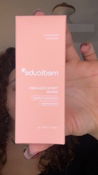 Różowe prostokątne pudełko z napisem "medicude" i "Triple Collagen Serum", zawierające minimalną ilość tekstu oraz zaokrąglone rogi. Pojemność 55 ml, 1,88 fl oz.