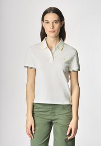 Polo bianco con strisce verdi e gialle di accento sul collo e sulle maniche. Design a maniche corte con un logo sul petto.