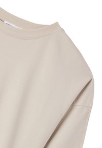 Top beige a maniche corte in morbido cotone, con un ampio scollo e dettagli di cucitura sottili. La texture appare liscia e leggera.