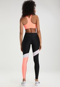 Soutien-gorge de sport athlétique en rose néon et leggings taille haute avec un coloris en bloc noir, blanc et rose, fabriqués dans un tissu extensible et respirant.