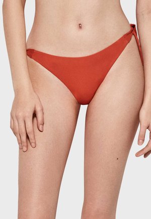 Parte inferior de bikini color óxido, con una textura suave, diseño de cintura baja y lazos laterales. Estilo simple y minimalista, sin patrones ni hardware distintivo.