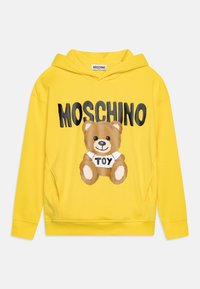 Felpa gialla con cappuccio, caratterizzata da una grafica di un orsetto marrone con la scritta "MOSCHINO TOY". Realizzata in tessuto morbido con polsini e orlo a costine.