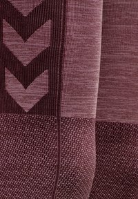 Ciemnofioletowa tkanina o teksturze z wzorami w zygzaki i kropki, o gładkim wykończeniu i widocznych szwach wzdłuż szwów.