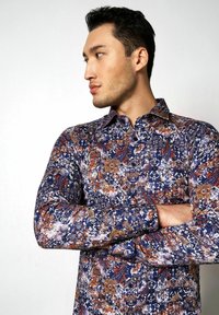 Langärmliges Hemd mit einem komplizierten Paisleymuster in Blau, Rot und Weiß; mit Knopfkragen; aus Baumwollmaterial; normale Passform.