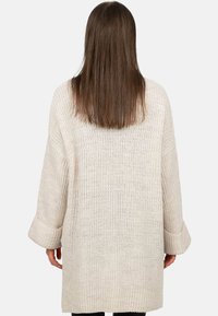 Licht beige gebreide cardigan met een losse pasvorm, brede mouwen en een stofpatroon, met ribbelmanchetten en zoomdetails.