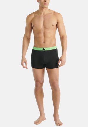 Zwarte boxershorts van rekbaar materiaal met een groene elastische tailleband met logo. Gladde textuur, aansluitend ontwerp, lengte tot halverwege de dijen.