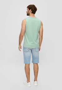 Mintgrünes ärmelloses Oberteil, hellblaue Denim-Shorts, weiße Sneakers. Einfaches Design mit lockerer Passform und ohne sichtbare Muster oder Akzente.