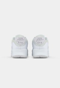 Zapatillas Nike Air con una parte superior de material sintético blanco, acentos en verde menta texturizados, un collar acolchado y un logotipo prominentemente situado en el talón.