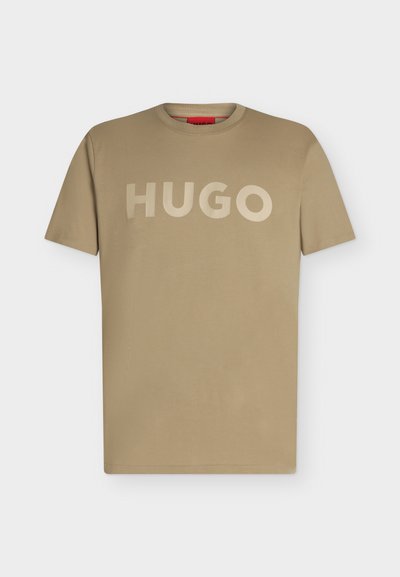 Обикновена къс ръкав бежова тениска с кръгла яка и голям текст „HUGO“ отпред в същия бежов нюанс.