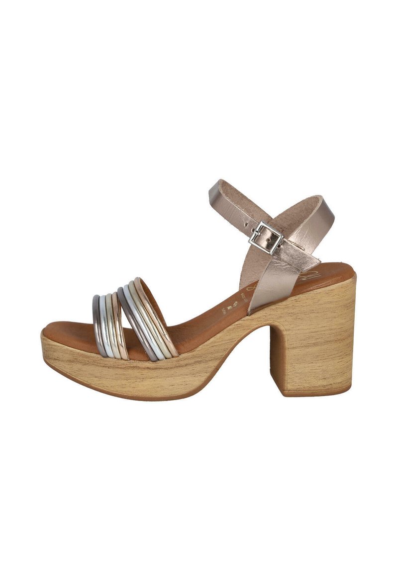 Sandalia con plataforma y tacón de madera gruesa, que presenta correas metálicas plateadas, una correa para el tobillo de cuero beige y un diseño de punta abierta.