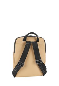 Zaino in tela color tan con spallacci neri regolabili, maniglia superiore, chiusura con zip e design minimalista. Presenta dettagli del logo sugli spallacci.