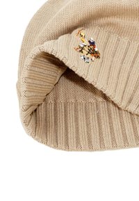 Beige kötött sapka bordázott textúrával, amelyen elöl többszínű hímzett lovaspólós részlet található.
