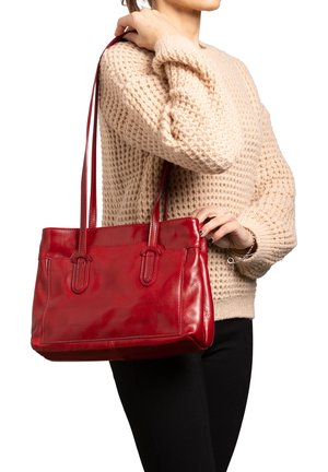 Borsa tote rossa in pelle con texture liscia, manici superiori doppi e dettagli di cucitura esterna, tenuta da una persona che indossa un maglione beige.