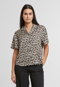 Halenka s krátkým rukávem v leopardím vzoru z hladké, lehké látky; má límec a zapínání na knoflíky, s volným střihem.