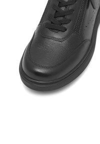 Čierna kožená topánka so zaoblenou špičkou, textúrovaným vrchom, šnurovaním a bočným zipsom. Hladký povrch, gumová podrážka a minimálne švy.