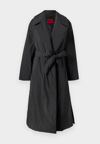 Abrigo negro hasta la rodilla, de tela ligera y texturizada, con solapas anchas, cinturón atado y un corte cómodo. Interior forrado con una etiqueta roja llamativa.