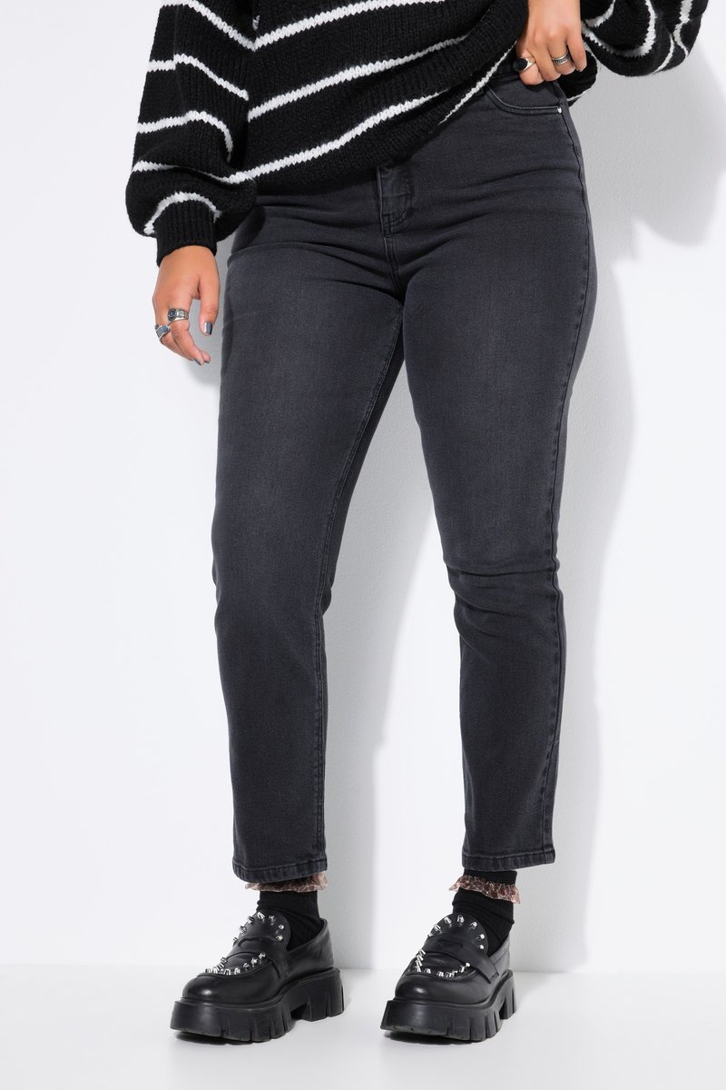 Personne portant un jean skinny taille haute noir, un pull rayé noir et blanc, et des chaussures épaisses noires avec des clous métalliques.