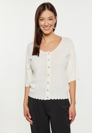 Cardigan bianco lavorato a maglia con maniche a 3/4, orlo scallop e bottoni al centro. Presenta un motivo a rombi e una texture morbida.