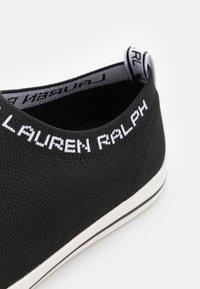Černé pletené tenisky s bílým nápisem "LAUREN RALPH" na límci, s bílou podrážkou a jemnými černými detaily.