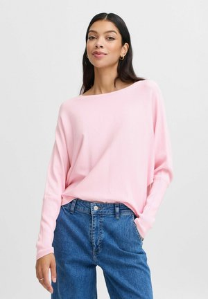 Light pink, long-sleeve sweater with a wide boat neckline, paired with blue denim jeans. Soft texture and relaxed fit.