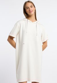 Witte hoodie-dress met korte mouwen, voorzien van roze stikselaccenten en een relaxte pasvorm. Gemaakt van zachte stof met een subtiele logo-detail.