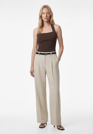 Femme portant un top marron à col carré et dos nu, un pantalon beige plissé taille haute avec une ceinture noire, et des sandales noires à talons.