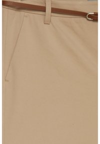 Pantalon beige avec une texture lisse, des plis latéraux et une ceinture en cuir marron avec une boucle argentée.