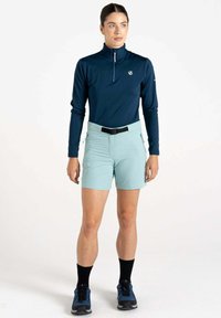 Marineblaues Langarmshirt mit einem Halb-Zip-Kragen, kombiniert mit hellblauen Shorts mit einem Gürtel und schwarzen Sneakersocken, die zu den sportlichen Schuhen passen.