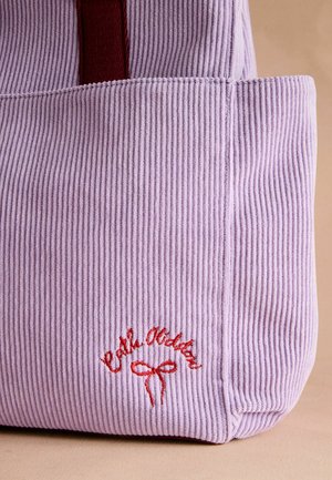 Lavendel corduroy schoudertas met rode accenten. Heeft een ribbeltextuur en geborduurde tekst met een strikdetail. Middenformaat, zachte constructie.