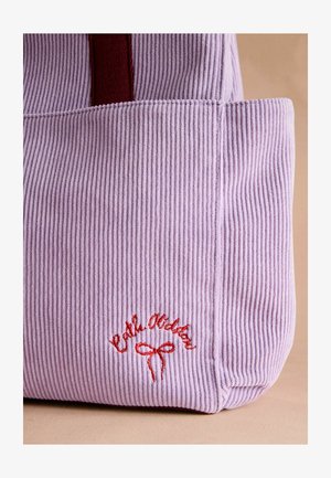 Borsa a spalla in corduroy lavanda con accenti rossi. Presenta una texture rigata e un testo ricamato con un dettaglio a fiocco. Di dimensioni medie e costruzione morbida.