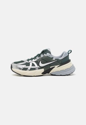 Zapatilla deportiva con una parte superior de malla verde, acentos plateados y una entresuela negra. Cuenta con una suela de goma gruesa y un cuello acolchado para mayor comodidad.