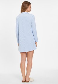 Helles blau gestreiftes Hemdkleid mit langen Ärmeln und Kragen, aus weichem Stoff. Es hat eine Brusttasche und einen lässigen Schnitt.