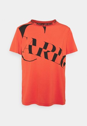 Oranžové bavlněné tričko s krátkými rukávy, s velkým černým nápisem "CARLO" v grafickém designu. Zaoblený výstřih s detailem loga.
