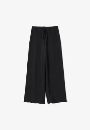 Zwarte wijde broek met een gestructureerde stof en een trekkoord in de taille, plat gelegd tegen een witte achtergrond.