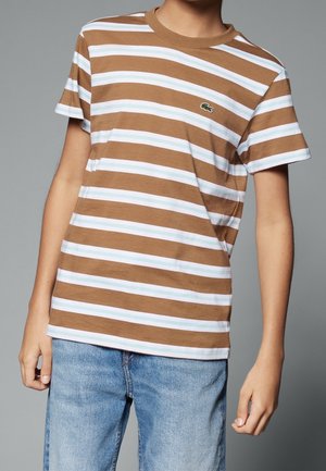 T-shirt rayé marron et blanc avec des accents bleu clair. Doté d'un col rond et de manches courtes. Logo Lacoste sur la poitrine.