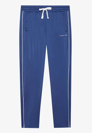 Sinised spordipüksid, millel on paelatest ümber ümber keha, valged külje triibud ja kaks esimest taskut. Esiküljel on tekst "PIER ONE".