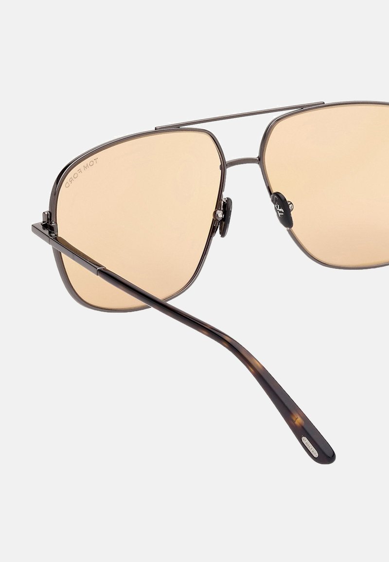 Metal aviator sunglasses with light brown lenses, a thin silver frame, and a tortoiseshell-patterned temple with logo detail.