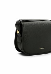 Sac à bandoulière en cuir noir avec une texture granuleuse, forme arrondie, accents en métal doré et fermeture à rabat sur le devant. Le nom de la marque est subtilement embossé.