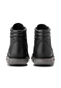 Botines de cuero negro con cuellos acolchados, paneles texturizados y suelas de goma gris con patrones de relieve distintivos.