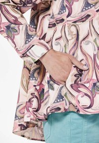 Patterned long-sleeve shirt in soft fabric features floral and abstract designs in shades of pink, purple, and green. Includes side pocket.