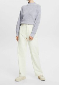 Lichtgrijze geribde trui met een col, gecombineerd met crèmekleurige wijde broekspijpen en beige sneakers, met een ontspannen pasvorm en textuur.