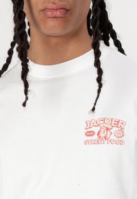 White cotton t-shirt featuring a colorful graphic logo "JACKER STREET FOOD" on the chest with dog illustration and bold text accents.